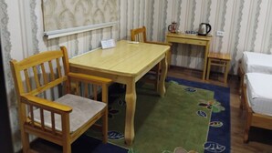 A room with a wooden table, two chairs, a small wooden stool, and a bed with a white sheet. - Gostevoy dom HOTEL ALLANAZAR OTA (Khiva)