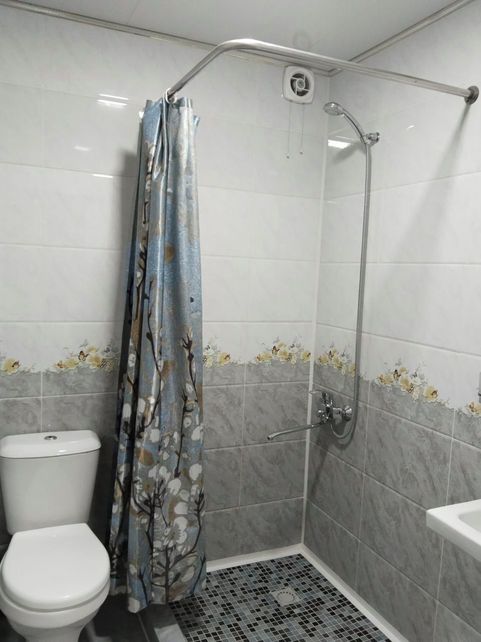 Un bagno con doccia, WC e pavimento piastrellato.