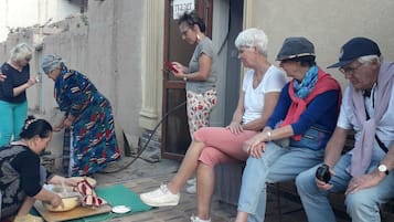 A group of people sitting and standing on a tiled patio area with a building in the background.