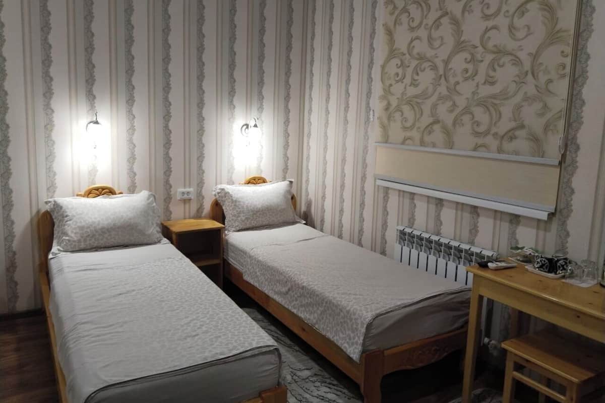 A room with two single beds, a desk, and a mirror.