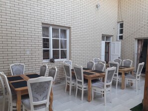 A dining area with a brick wall, white chairs, and a wooden table.