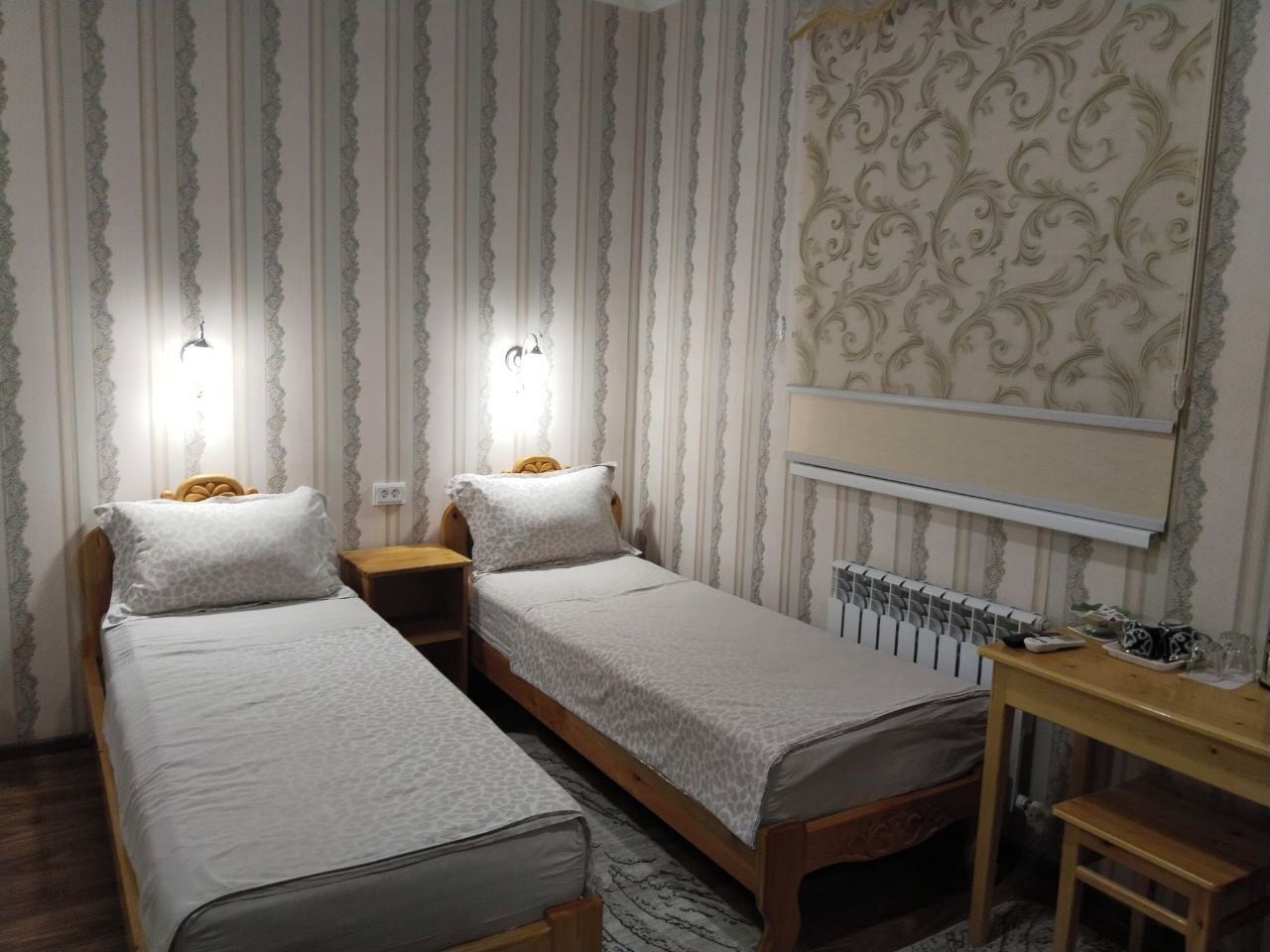 A room with two single beds, a desk, and a mirror.