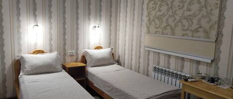 A room with two single beds, a desk, and a mirror.