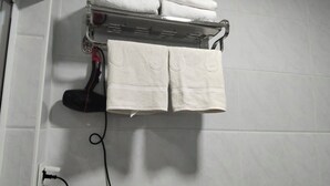 A bathroom with a towel rack holding folded towels and a hairdryer. - Gostevoy dom HOTEL ALLANAZAR OTA (Khiva)