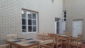 Una habitación con pared de ladrillo, ventana, puerta y una mesa con sillas.