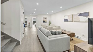A modern living room with a sofa, coffee table, and artwork on the wall. - Nature, Comfort retreat | La Grande Escapade (Saint-Donat-de-Montcalm)