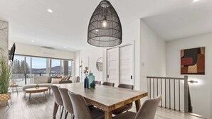 A modern dining area with a wooden table, chairs, and a hanging light fixture. - Nature, Comfort retreat | La Grande Escapade (Saint-Donat-de-Montcalm)