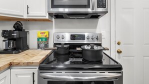 Una cocina con microondas, estufa, cafetera y una caja de té Lipton.