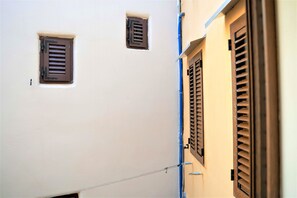 A narrow alleyway with two small windows and a door with shutters. - Casa Luigi Studio 3 – Calm & Central Old Town (Rovinj)