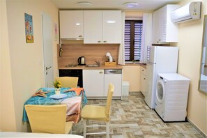 A compact kitchen with white cabinets, a sink, a coffee maker, and a washing machine. - Casa Luigi Studio 3 – Calm & Central Old Town (Rovinj)