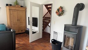 Uma sala de estar com lareira, um armário de madeira, uma televisão e uma escada.