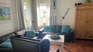 Uma sala de estar com sofá, mesa de centro, abajur e armário.