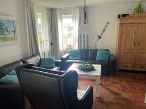 A living room with a sofa, a coffee table, a lamp, and a cabinet. - Cozy vacation home with sauna and fireplace in Maasholm-Bad (Maasholm)