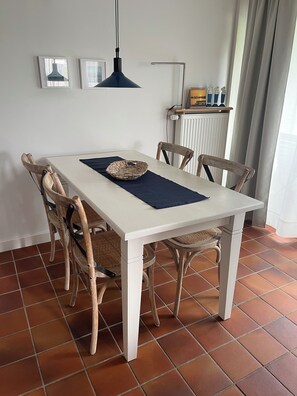 A dining table with four chairs, a woven placemat, and a pendant light. - Cozy vacation home with sauna and fireplace in Maasholm-Bad (Maasholm)