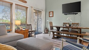 Una habitación con un ventanal grande, televisor, mesa de comedor y sofá.