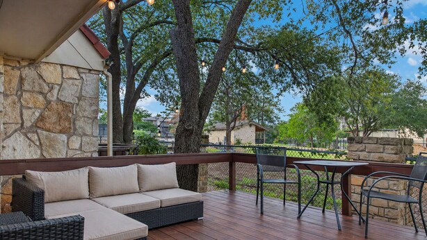 Un espacio de estar al aire libre cubierto con pared de piedra, terraza de madera y mobiliario exterior.