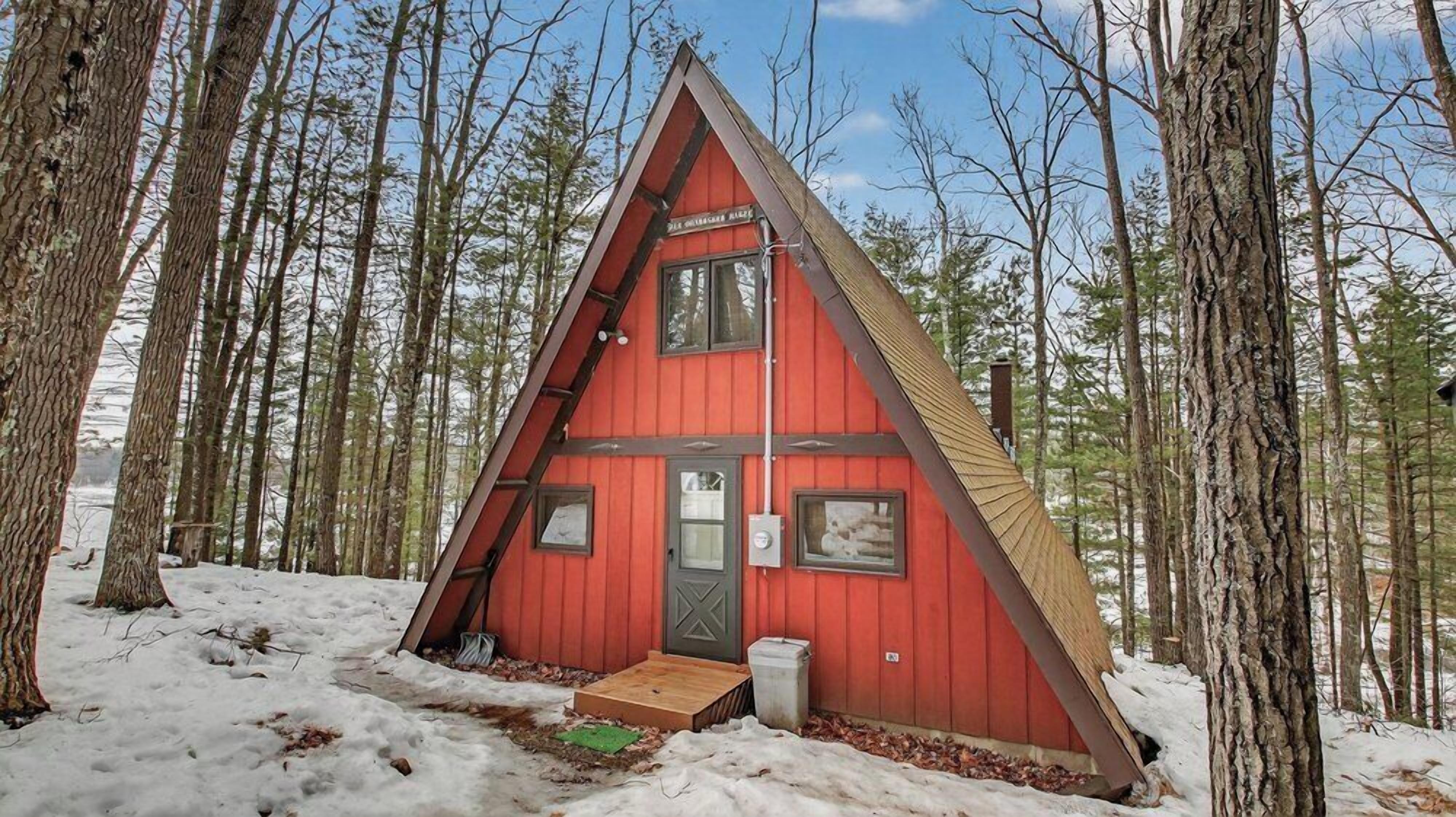 Charming A-frame cabin nestled in snow-dusted woods offers the perfect winter retreat for your peaceful getaway.
