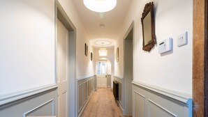 Un corridoio con pavimento in legno, pareti bianche, una luce a soffitto e una porta in fondo.