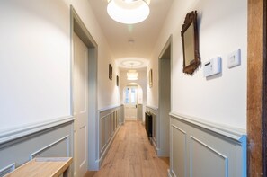 A hallway with a wooden floor, white walls, a ceiling light, and a door at the end. - Coachman's House | Luxury Stay Near NEC | Sleeps 8 (Birmingham)