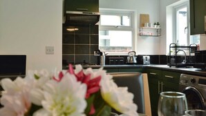 Una cocina moderna con horno empotrado, cafetera y ventana sobre el fregadero.