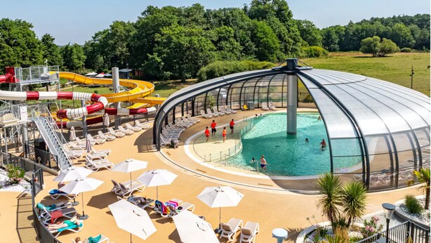 Un área de piscina con una estructura en forma de cúpula, tumbonas y un tobogán de agua.