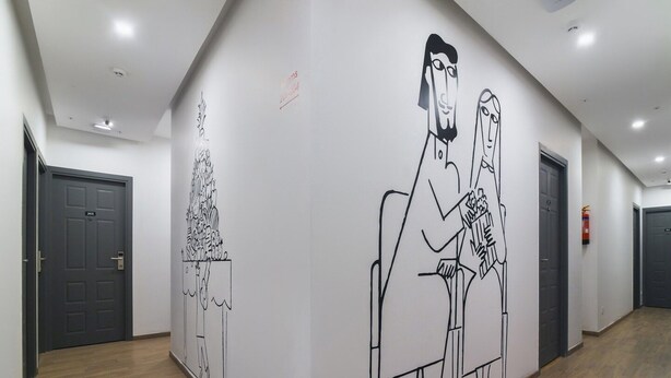 Un couloir orné d’une grande fresque murale en noir et blanc, une porte portant l’inscription « 201 », et un extincteur fixé au mur.