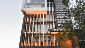 Un hôtel moderne à l’architecture verticale remarquable, avec une enseigne indiquant « OYO TOWING HOUSE » et un escalier menant à l’entrée.