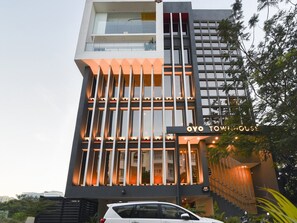 Ein modernes Hotel mit markantem vertikalen Design, einer Schrifttafel mit der Aufschrift 'OYO TOWING HOUSE' und einer Treppe, die zum Eingang führt.