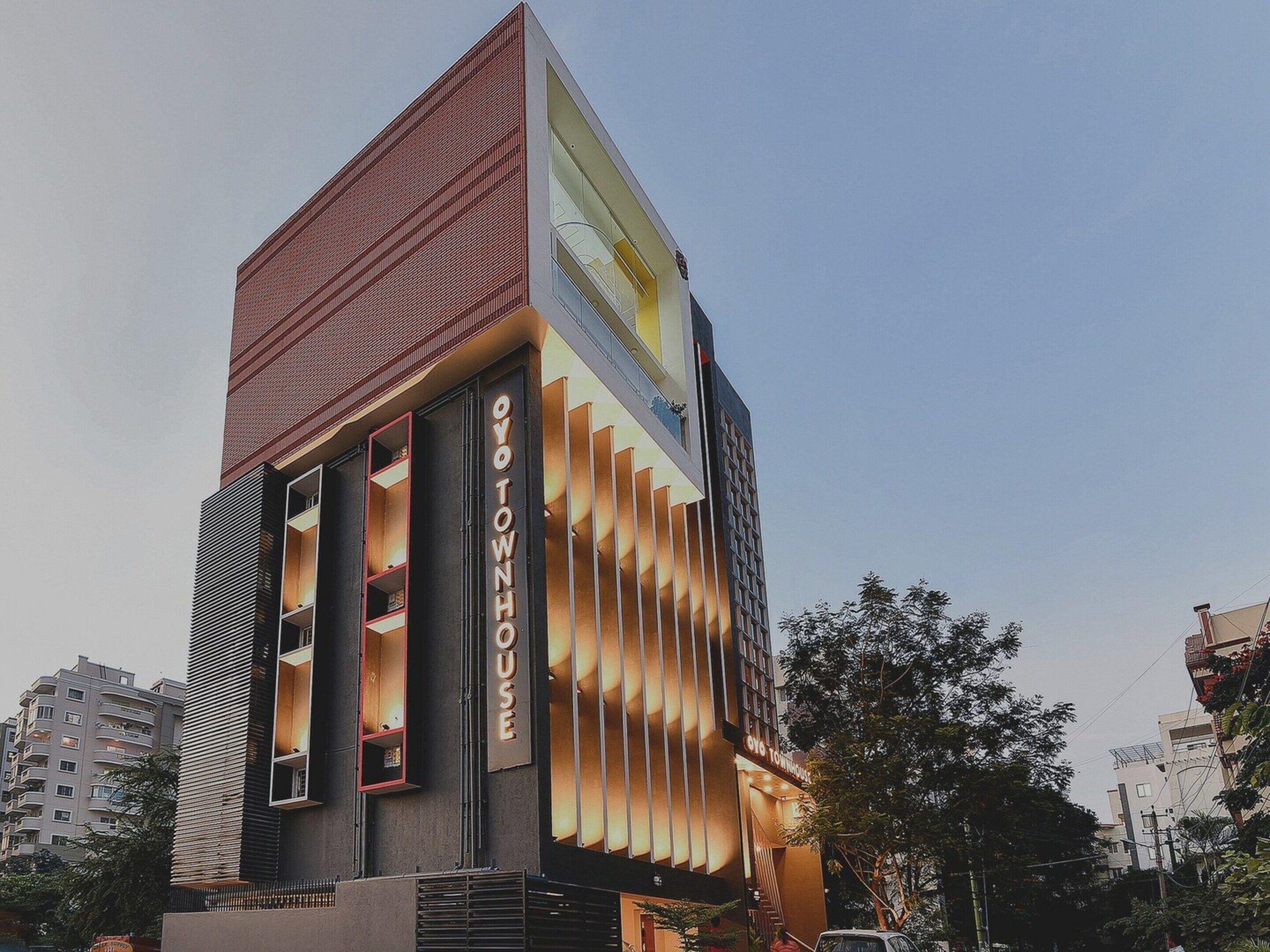 Un bâtiment moderne avec une grande enseigne verticale bien visible, sur laquelle on peut lire « OYO TOWNHOUSE ».