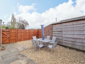 A patio with a table and chairs, a wooden fence, and a brick wall. - Field View (North Walsham)