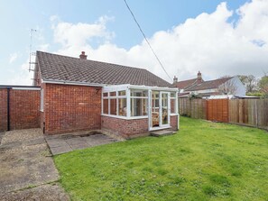 A brick house with a conservatory, a fenced yard, and a clear sky. - Field View (North Walsham)