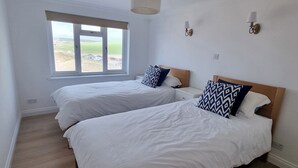 Ein Schlafzimmer mit zwei Betten, einem Fenster mit Blick und einer Wandlampe.