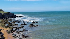 Eine Küstenlandschaft mit felsigen Ufern, blauem Himmel und ruhiger See.