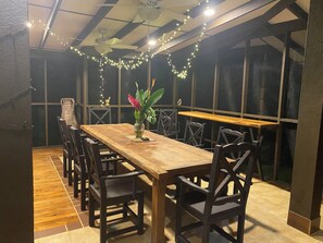 A dining area with a wooden table, chairs, and string lights. - Magnificent Hotel Hacienda de Los Sueños, Ojochal, Costa Rica, capacity 16@18 pers (Ojochal)