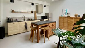 A modern kitchen with wooden cabinets, a dining table, and pendant lighting.