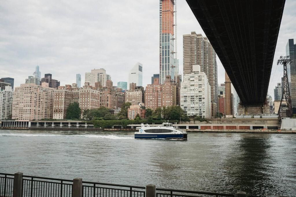A city skyline with a river, a bridge, and a boat.