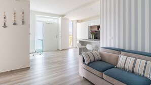 Una sala moderna con un sofá, un ventanal de vidrio que da a otra habitación y una pared a rayas.