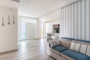 Ein modernes Wohnzimmer mit einer Couch, einer Glastür zu einem anderen Raum und einer gestreiften Wand.