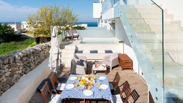 Terraza en la azotea con piscina, mobiliario exterior y mesa lista para el desayuno.