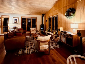 Ein gemütliches Wohnzimmer mit Holzwänden, einem Kamin, einer Couch, einem Couchtisch und einem Fernseher.