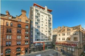 A multi-story building with a modern glass facade, adjacent older brick buildings, and a clear sky. - Stylish 2BR City Centre Flat | 3 min to Central Station | Family Sized (Glasgow)