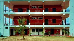 A multi-story building with balconies, a central entrance, and a clear sky. - Nischala Stay at Isha Yoga Center (Coimbatore)