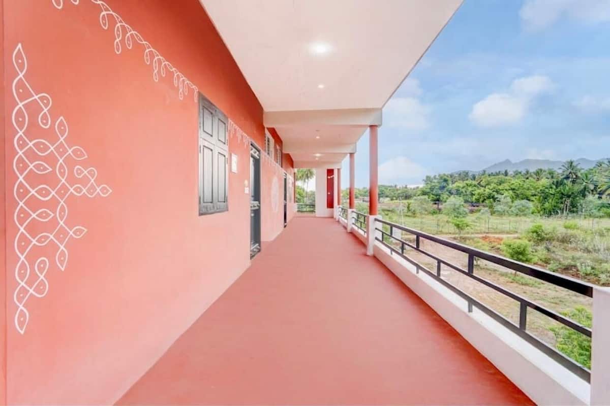 A corridor with a red floor, white railings, and a view of greenery and mountains in the distance.