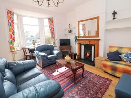 Una sala de estar con sofá, sillón, televisión, chimenea y alfombra estampada.
