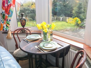 A dining table set for two with plates, cutlery, and a vase of yellow flowers. - Glenside Lodge (High Peak)