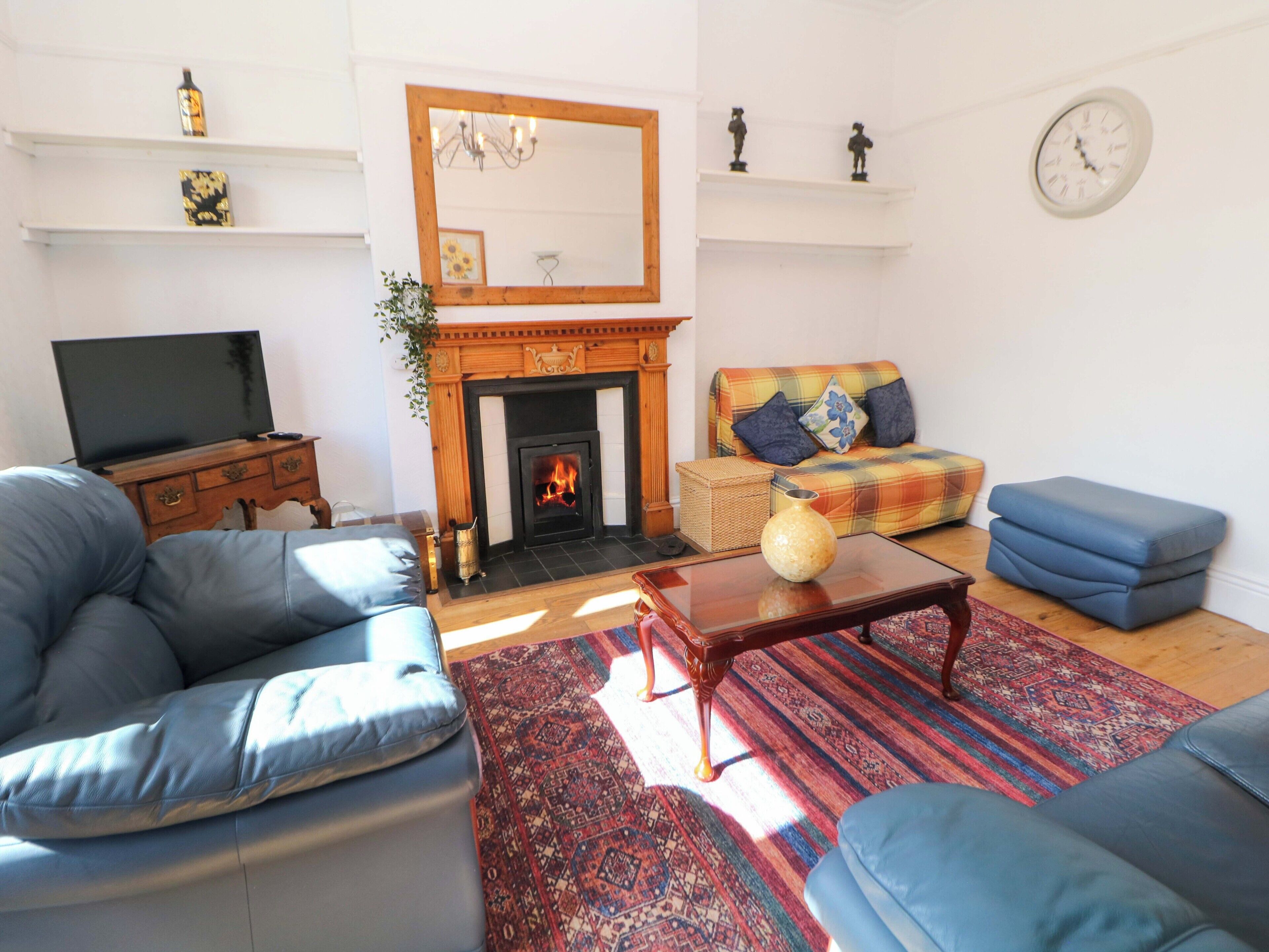 A living room with a fireplace, sofas, a television, and a clock on the wall.