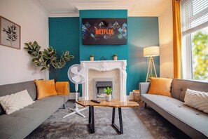 A living room with a fireplace, two sofas, a coffee table, and a TV mounted on the wall displaying 'NETFLIX'. - Blue Lagoon Retreat Escape | Free Parking | 16PPL (Sheffield)