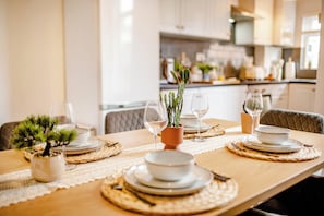 A dining table set with plates, bowls, and cutlery, with a potted plant and a vase of flowers. - Blue Lagoon Retreat Escape | Free Parking | 16PPL (Sheffield)