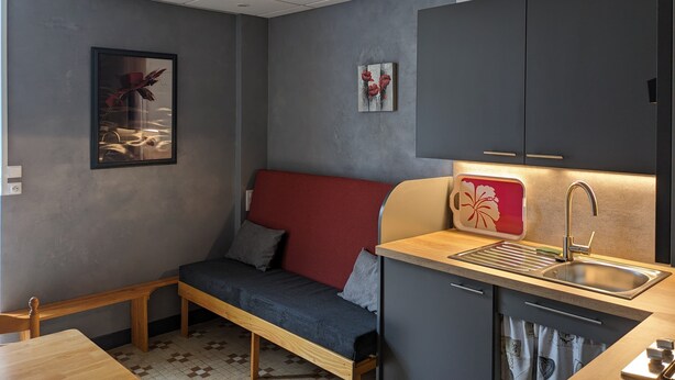 Una kitchenette compacta con un lavamanos, una pequeña mesa de comedor y un banco.