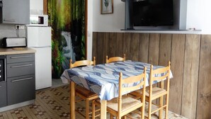 Una cocina equipada con microondas, tostadora y refrigerador. Hay una mesa de comedor con sillas y un cuadro en la pared.